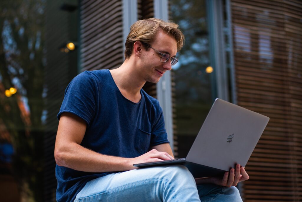 Student looking in a positive state of mental wellbeing sat on his laptop